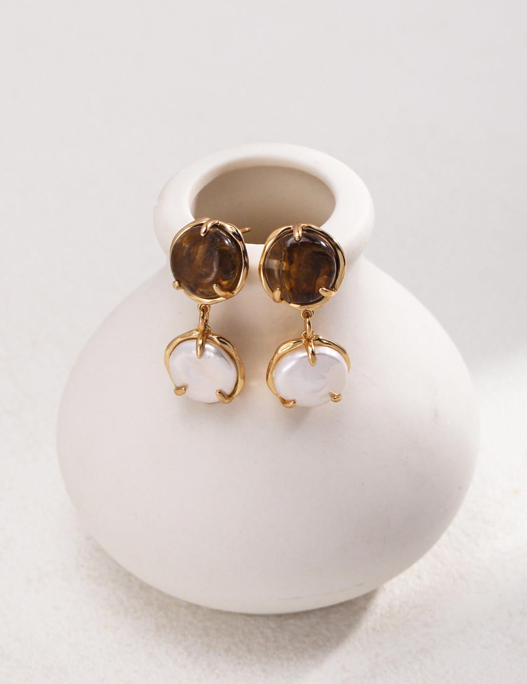 Charming Coffee and Milk-Inspired Earrings featuring captivating brown resin and lustrous natural pearls. Crafted from high-quality S925 silver with a vintage gold finish, these earrings have a height of approximately 3.2cm and a bead diameter of about 1.2cm. Their sophisticated yet whimsical design makes them perfect for everyday wear or special occasions.