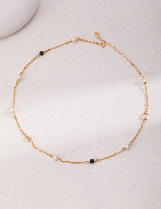 Éclat necklace in 925 sterling silver with natural pearls, black agate, and zircon accents, finished in vintage gold. Adjustable chain length 38cm + 6cm extension, featuring 5.7mm pearls, 4mm agate, and 7mm x 4.8mm zircon for a sophisticated look.