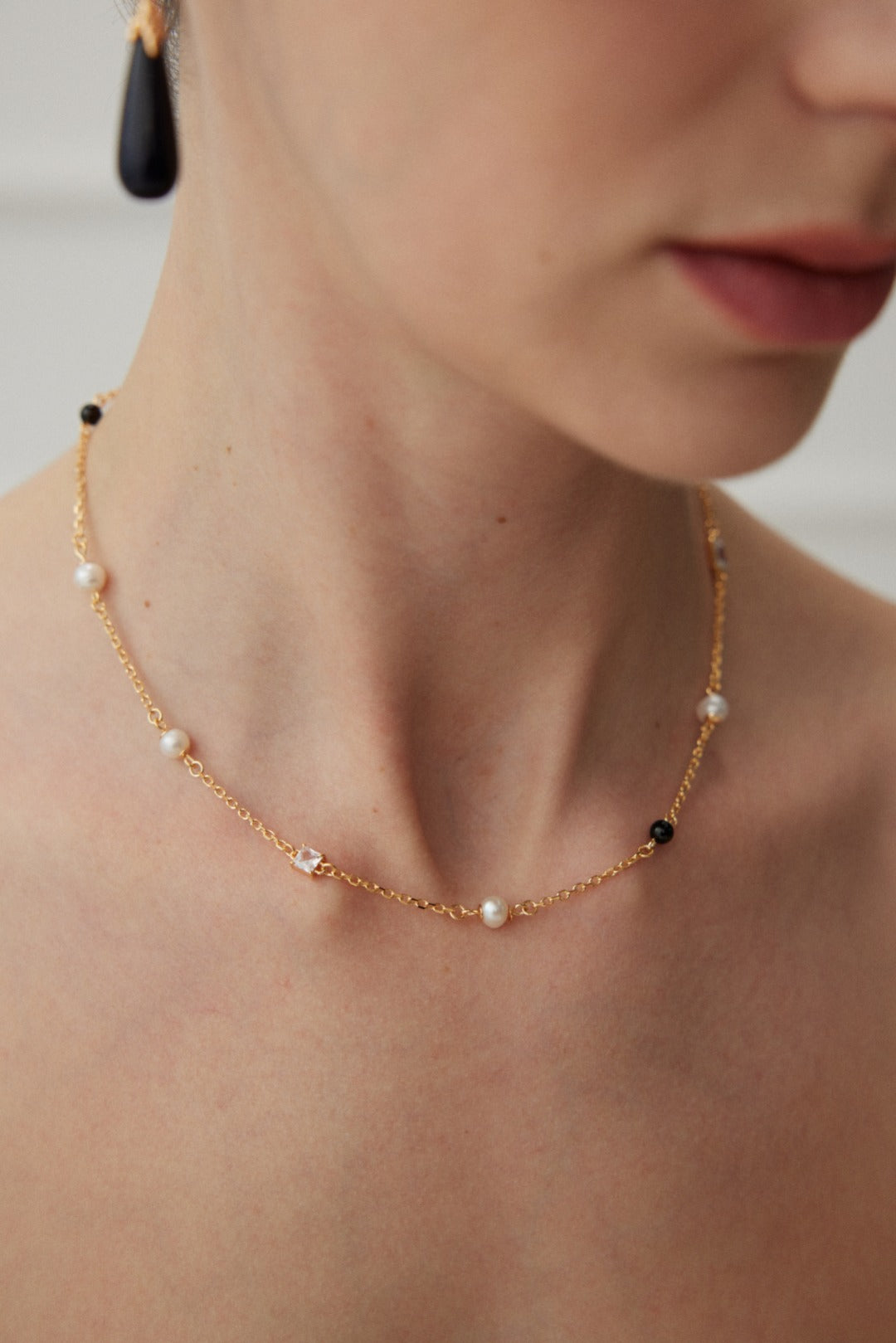 Éclat necklace in 925 sterling silver with natural pearls, black agate, and zircon accents, finished in vintage gold. Adjustable chain length 38cm + 6cm extension, featuring 5.7mm pearls, 4mm agate, and 7mm x 4.8mm zircon for a sophisticated look.