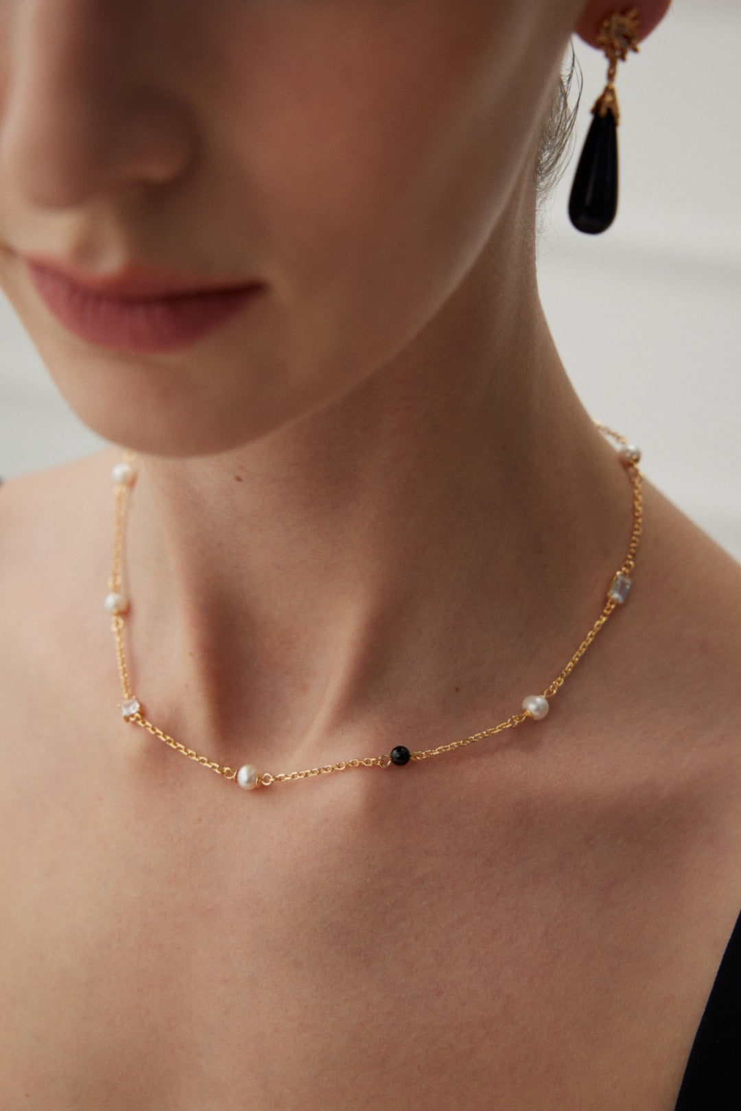 Éclat necklace in 925 sterling silver with natural pearls, black agate, and zircon accents, finished in vintage gold. Adjustable chain length 38cm + 6cm extension, featuring 5.7mm pearls, 4mm agate, and 7mm x 4.8mm zircon for a sophisticated look.